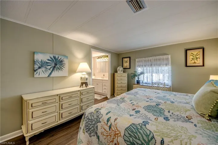 Bedroom featuring visible vents, ornamental molding, connected bathroom, and dark wood-style floors