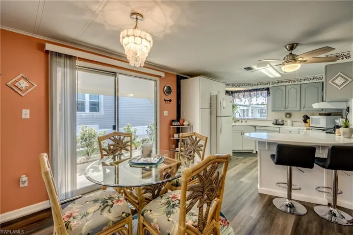 Dining area featuring crown molding, ceiling fan with notable chandelier, dark wood finished floors, and visible vents