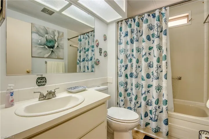 Bathroom featuring vanity, shower / bath combination with curtain, toilet, and visible vents
