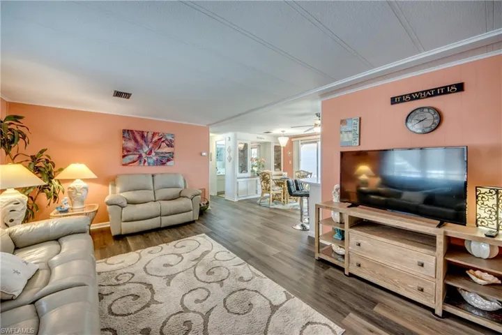 Living room featuring visible vents, baseboards, ceiling fan, and wood finished floors