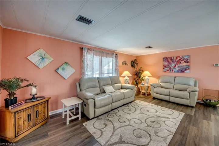 Living room featuring visible vents, ornamental molding, and wood finished floors