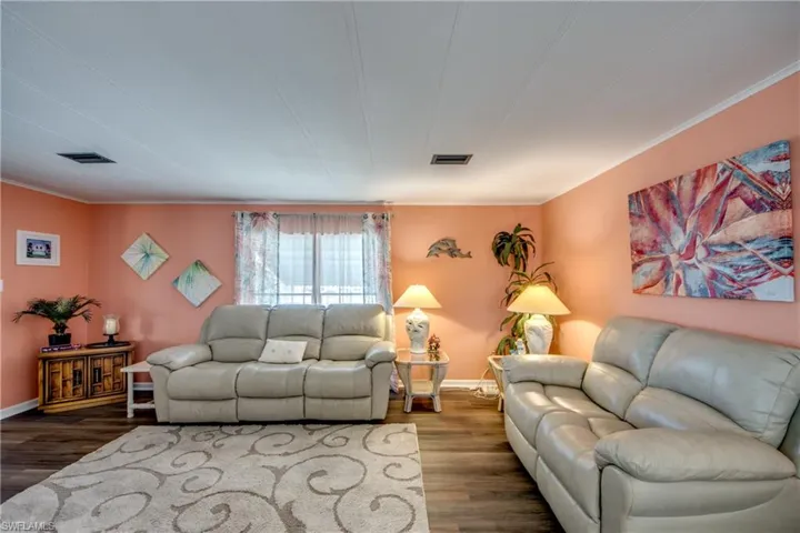 Living room featuring visible vents, crown molding, and wood finished floors