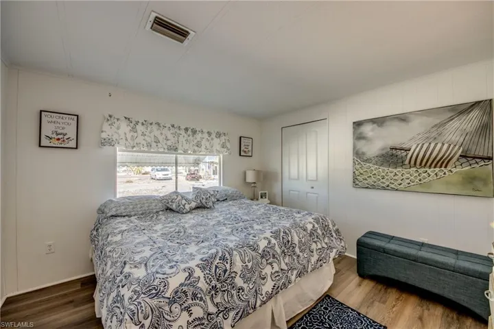 Bedroom with visible vents, baseboards, wood finished floors, and a walk in closet