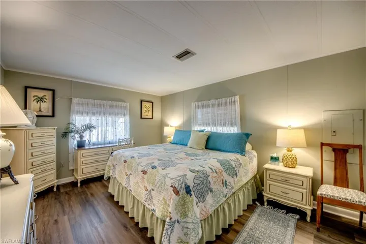 Bedroom with crown molding, dark wood-style floors, and visible vents