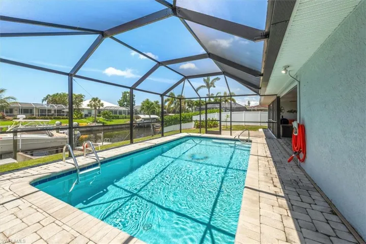 View of swimming pool with a water view, a patio, and glass enclosure