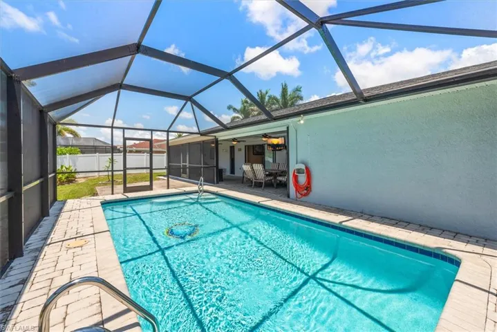 View of swimming pool featuring a patio area, a ceiling fan, and glass enclosure