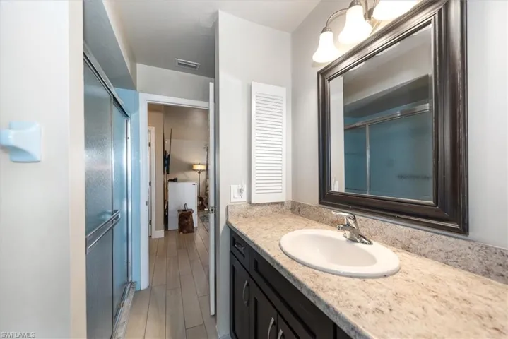 Full bathroom featuring vanity, an enclosed shower, and wood finished floors