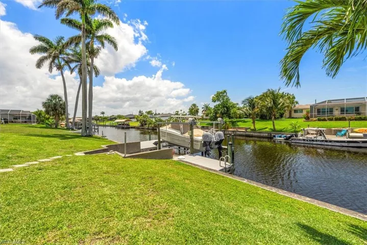 Dock area featuring a water view, a lawn, and boat lift