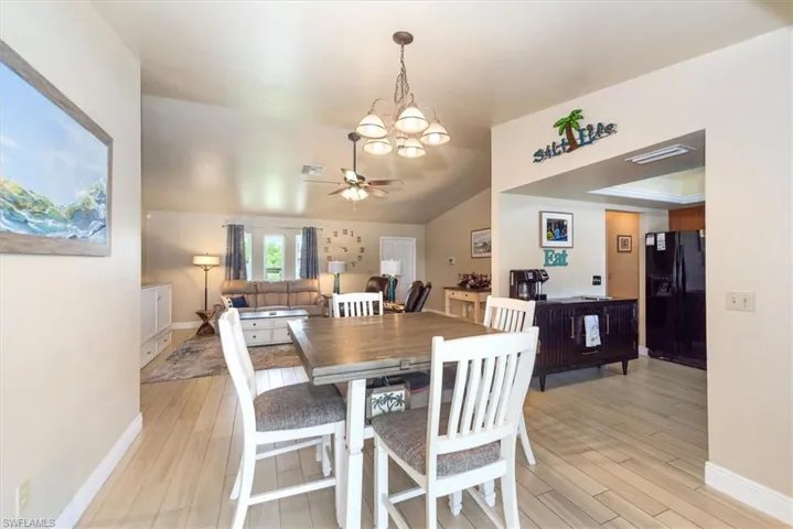 Dining space with a chandelier, light wood-style flooring, baseboards, and ceiling fan