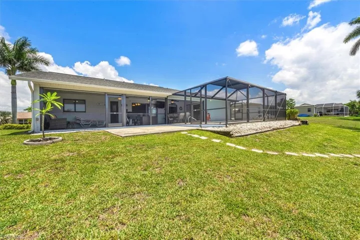 Back of house featuring a lawn, a patio area, and glass enclosure