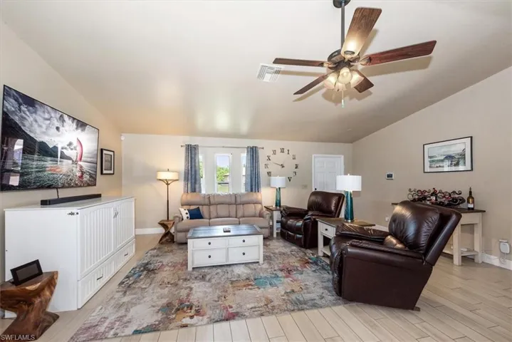 Living area with lofted ceiling, wood finished floors, a ceiling fan, and baseboards