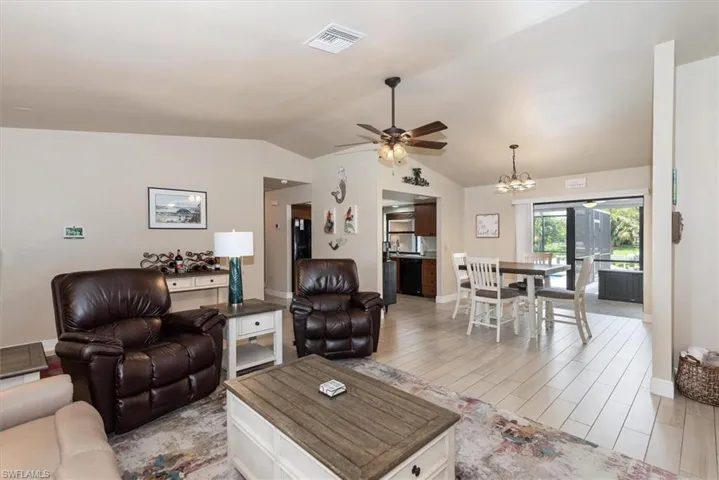 Living area featuring ceiling fan, vaulted ceiling, a chandelier, light wood-style flooring, and baseboards