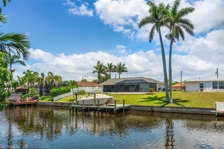 Dock area featuring a water view, a yard, and glass enclosure