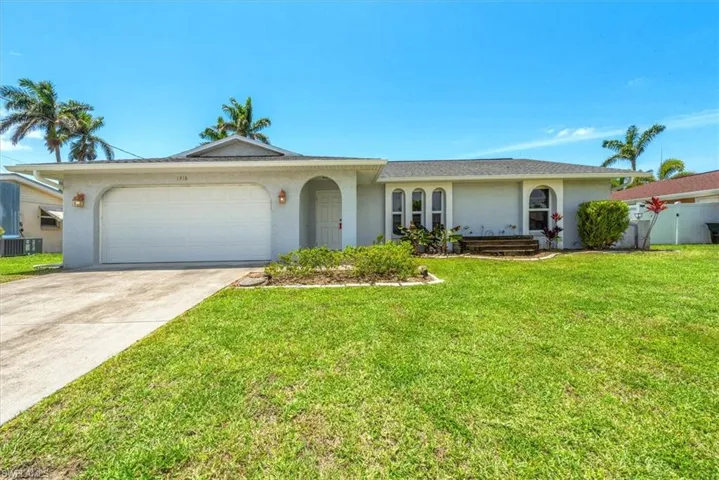 Single story home with stucco siding, central AC, an attached garage, concrete driveway, and a front lawn