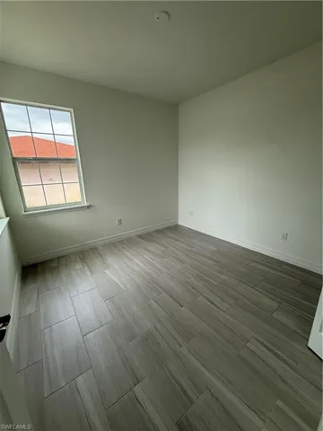 Spare room with baseboards and wood finish floors