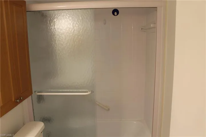Full bathroom with toilet and bath / shower combo with glass door
