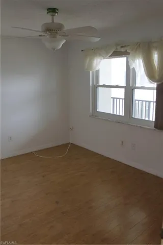 Spare room with wood finished floors, baseboards, a ceiling fan, and a textured ceiling