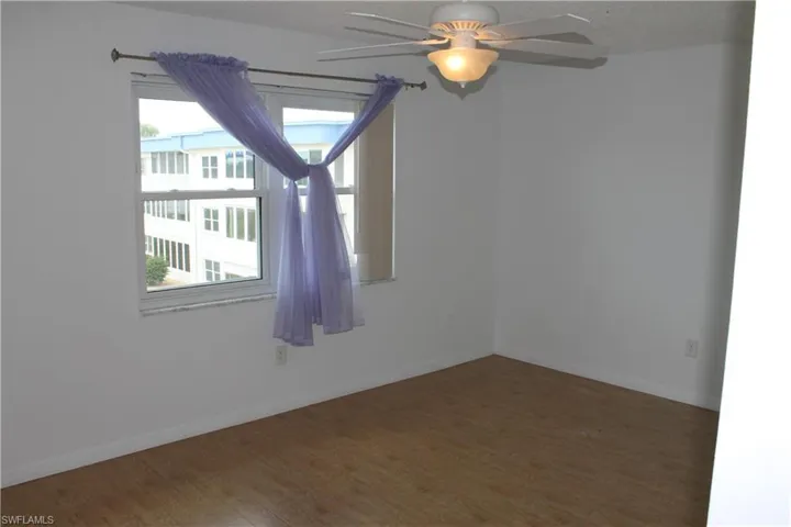 Spare room featuring wood finished floors, ceiling fan, and baseboards