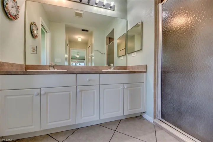 Full bath with a stall shower, tile patterned flooring, and double vanity