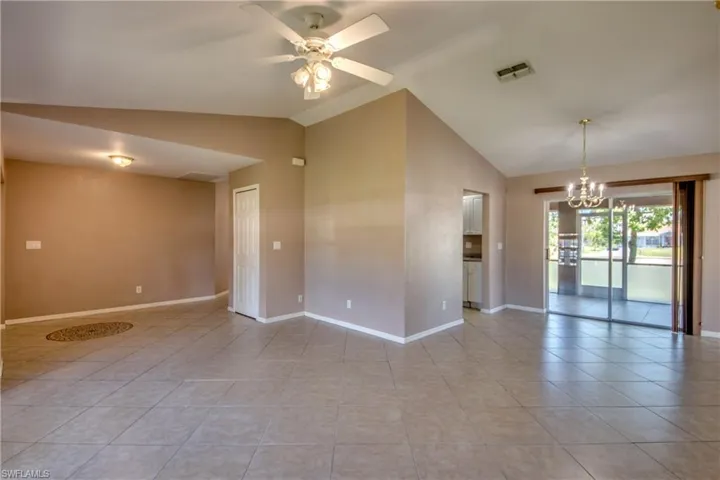 Unfurnished room with a chandelier, light tile patterned flooring, ceiling fan, baseboards, and high vaulted ceiling