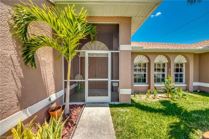 Entrance to property featuring stucco siding and a yard
