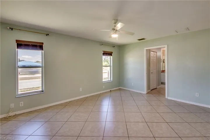 Unfurnished room featuring a ceiling fan, light tile patterned floors, and baseboards