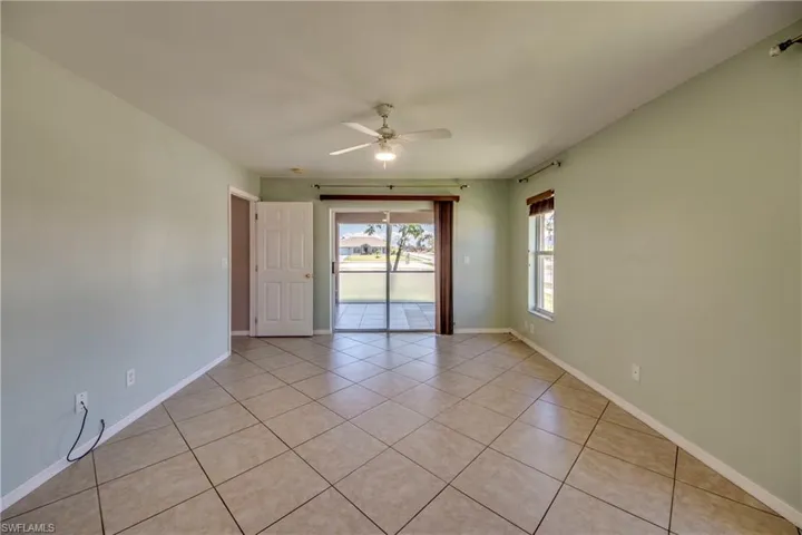 Spare room featuring light tile patterned flooring, ceiling fan, and baseboards