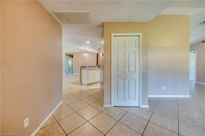 Hall with light tile patterned floors, baseboards, and a chandelier