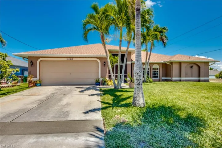 Ranch-style home with stucco siding, a garage, driveway, and a front lawn