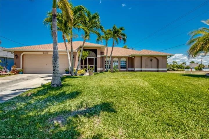 Ranch-style home featuring a garage, a front lawn, driveway, and stucco siding
