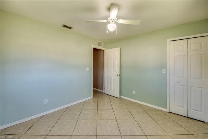 Unfurnished bedroom with a closet, light tile patterned floors, baseboards, and a ceiling fan