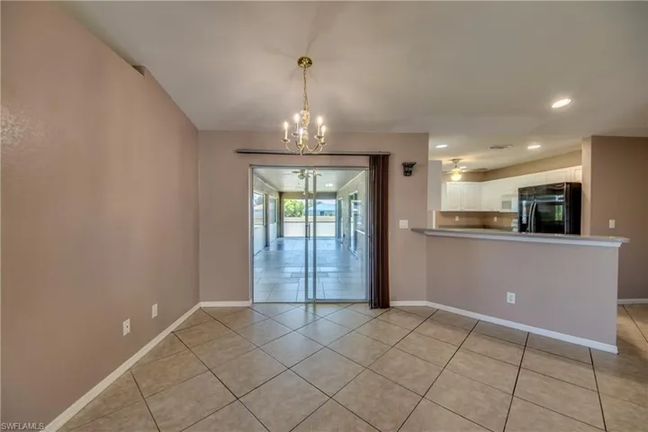 Unfurnished dining area featuring a chandelier, light tile patterned flooring, baseboards, recessed lighting, and a ceiling fan