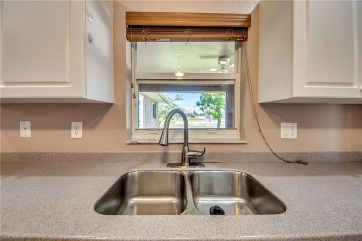 Kitchen with a sink, white cabinetry, a ceiling fan, and light countertops