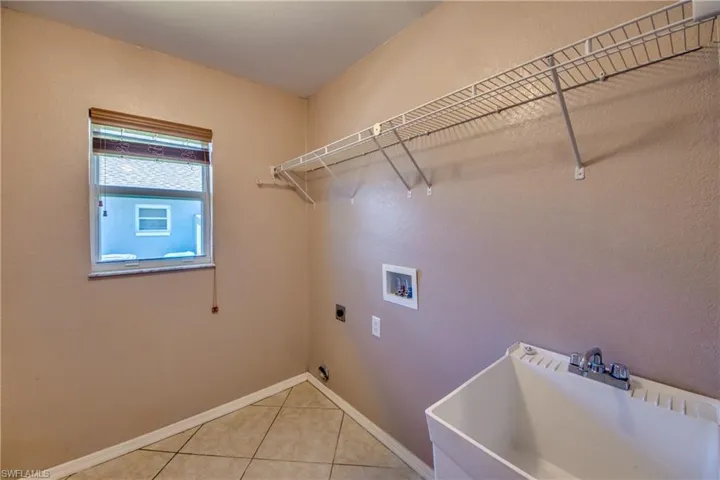 Washroom with washer hookup, hookup for an electric dryer, light tile patterned flooring, and baseboards