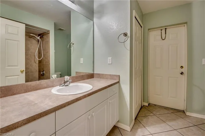 Full bathroom featuring tile patterned flooring, baseboards, toilet, a shower, and vanity