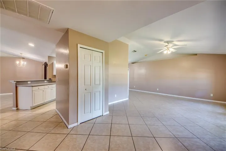 Spare room with lofted ceiling, light tile patterned flooring, a chandelier, ceiling fan, and baseboards