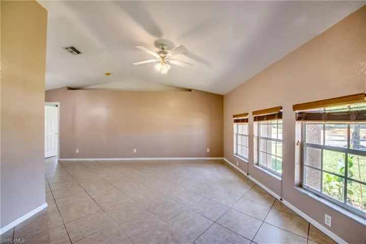 Unfurnished room with vaulted ceiling, ceiling fan, light tile patterned flooring, and baseboards