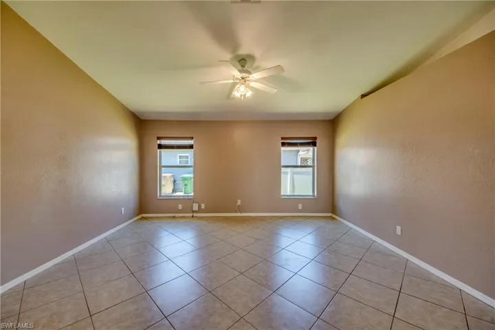 Spare room featuring ceiling fan, light tile patterned floors, and baseboards