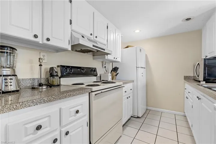 Kitchen featuring electric stove, light tile patterned floors, and white cabinets