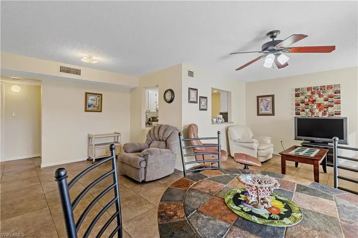 Tiled living room with ceiling fan and a textured ceiling