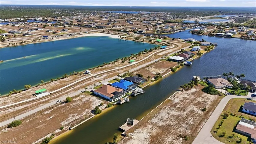 Aerial view of property and surrounding area featuring nearby suburban area and a nearby body of water
