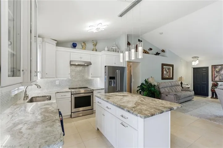 Kitchen with white cabinets, open floor plan, stainless steel appliances, backsplash, and a high ceiling