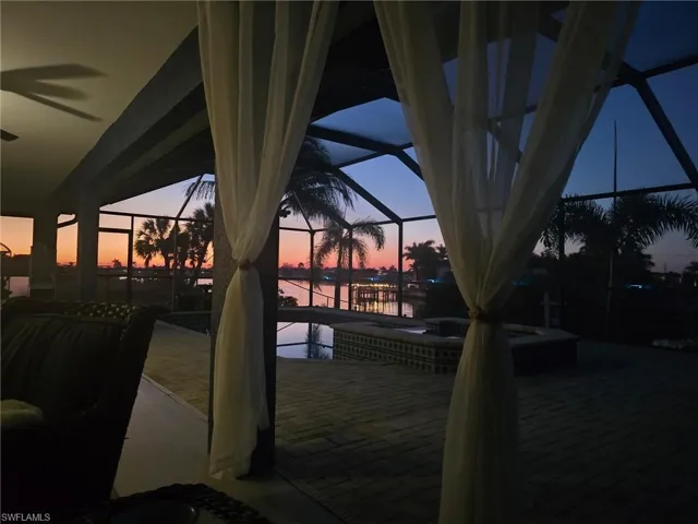 Patio terrace at dusk featuring a sunroom, a lanai, a patio, a jacuzzi, and an outdoor pool
