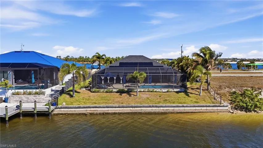 Dock area featuring a sunroom, a water view, a yard, glass enclosure, and an outdoor pool