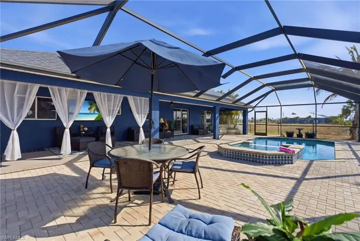 Combined pool / hot tub with a lanai, a sunroom, a patio area, and outdoor dining space