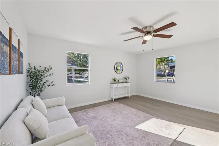 Living area with wood finished floors, plenty of natural light, and ceiling fan