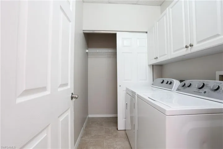 Laundry area featuring washing machine and clothes dryer, baseboards, cabinet space, and light tile patterned floors