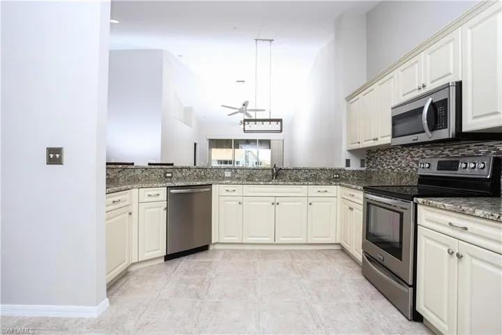 Kitchen with appliances with stainless steel finishes, dark stone countertops, backsplash, and a sink