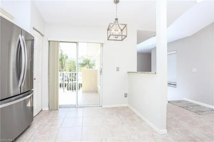 Kitchen featuring freestanding refrigerator, light tile patterned floors, a chandelier, and baseboards