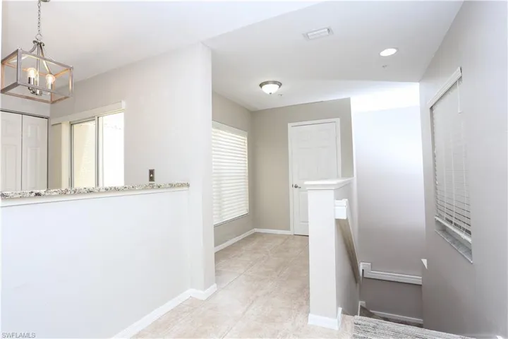 Corridor with a chandelier, an upstairs landing, baseboards, and light tile patterned floors